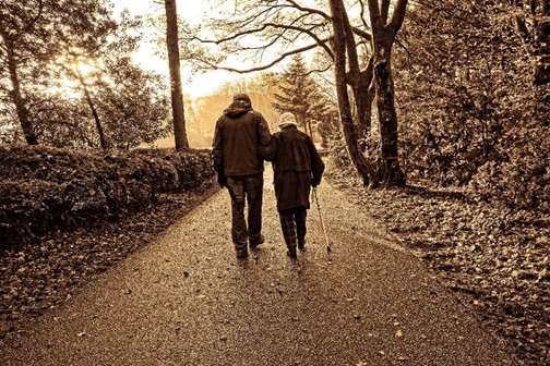 une personne avec sa canne et une seconde personne qui la guide